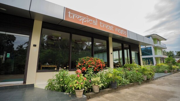 A modern building with a sign reading "tropical treat restaurant".