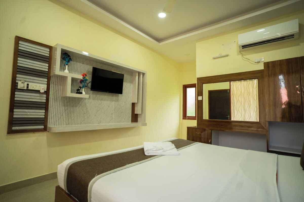 Une chambre d’hôtel équipée d’un lit, d’un téléviseur fixé au mur, d’un appareil de climatisation et d’une fenêtre avec des rideaux.