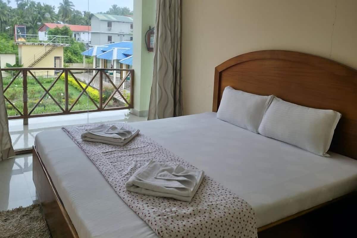 Quarto de hotel com uma cama grande, um ventilador de teto e uma varanda com vista para a região.