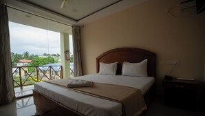 A bedroom with a large bed, a wooden headboard, a bedside table, and a view of the outdoors through a sliding door.