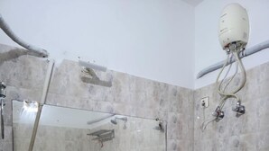 A bathroom with two sinks, a large mirror, and a shower with a ceiling-mounted water heater.