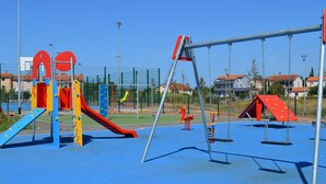 A playground with various play structures, including slides and swings, surrounded by a fence. - The apartment and free rental bikes, for families and active holidays (Pula)