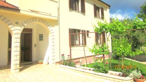A two-story building with a stone archway entrance, numbered 42, and a garden with potted plants and a pergola. - The apartment and free rental bikes, for families and active holidays (Pula)