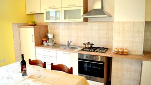 A compact kitchen with white cabinets, a gas stove, an oven, and a sink. - The apartment and free rental bikes, for families and active holidays (Pula)