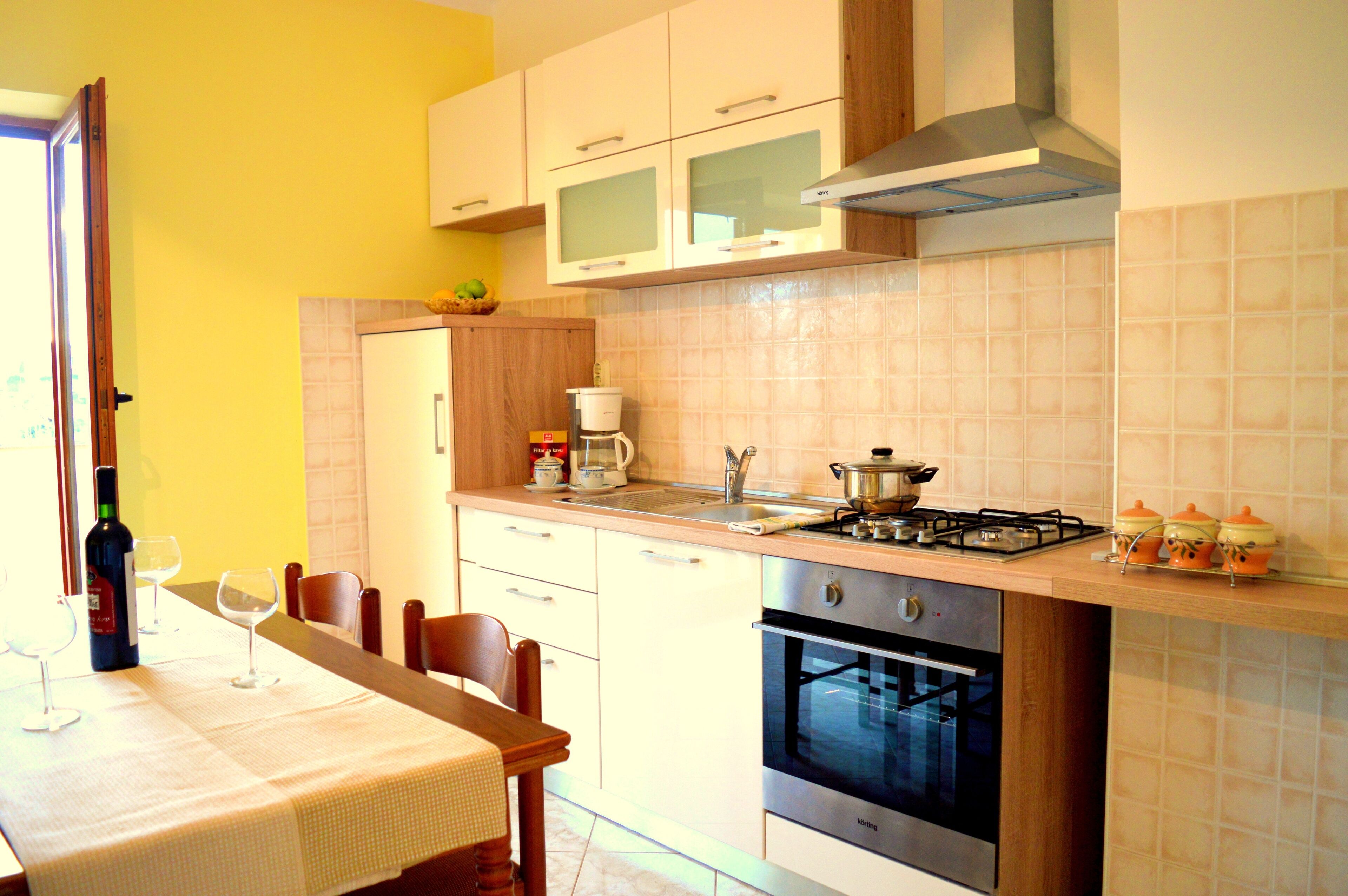 A kitchen with a dining table set for two, a stove, oven, and a microwave.