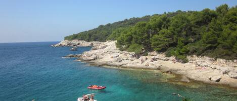 A coastal scene with clear turquoise water, rocky shores, and a boat.
