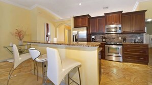 A modern kitchen with granite countertops, stainless steel appliances, and wooden cabinets. - HD Smart TV's, Kayaks, Pool & Spa, WIFI, Gulf Access, E-Dart Board, Bar, Grill  (Cape Coral)
