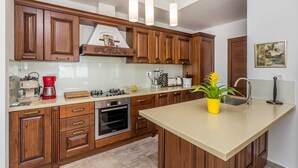 A modern kitchen with wooden cabinets, a gas stove, a coffee maker, and a sink. - Villa LURDA with a magnificent sea view and heated pool (Linardići)