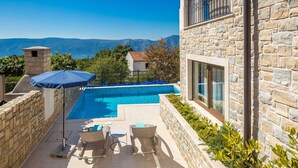 A stone building with a swimming pool, outdoor seating, and a view of mountains. - Villa LURDA with a magnificent sea view and heated pool (Linardići)