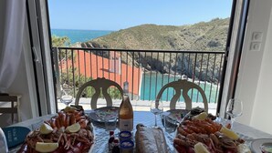 A table set with seafood, wine, and condiments, overlooking a coastal view.