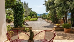 A patio with a table and chairs, surrounded by potted plants and a gravel path leading to a gate. - Holiday house with pool, air conditioning in the bedrooms, internet / outside kitchen with barbecue, (Pollensa)