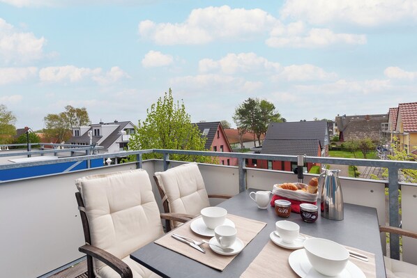 A balcony with a table set for two, chairs, and a view of the cityscape. - Flooded with light, close to the center, WLAN, 400 m z. Beach (Zingst)