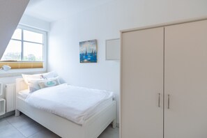 A bedroom with a bed, a nightstand, a lamp, a painting, and a wardrobe. - Flooded with light, close to the center, WLAN, 400 m z. Beach (Zingst)