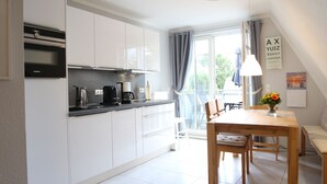 A modern kitchen with white cabinets, a black countertop, and a Siemens oven. There is a dining table with chairs and a vase of flowers. - Flooded with light, close to the center, WLAN, 400 m z. Beach (Zingst)