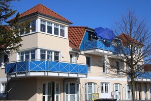 A multi-story building with a red-tiled roof, blue balconies, and a beige facade. - Flooded with light, close to the center, WLAN, 400 m z. Beach (Zingst)