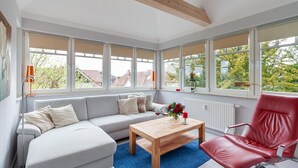 A modern living room with a grey sofa, a wooden coffee table, and a red chair. - Flooded with light, close to the center, WLAN, 400 m z. Beach (Zingst)