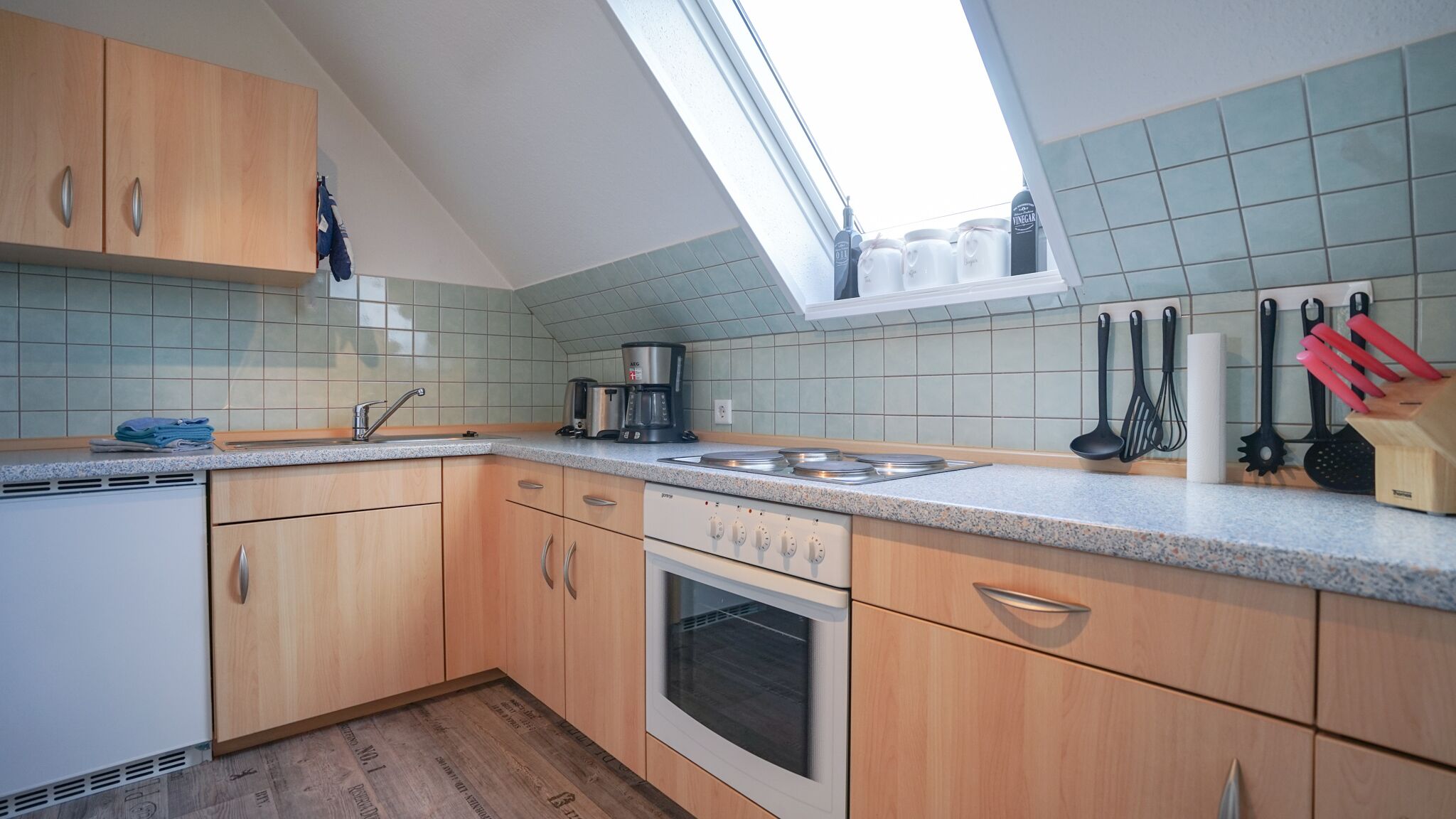 Cucina con mobili in legno, forno integrato, macchina da caffè e un lucernario.