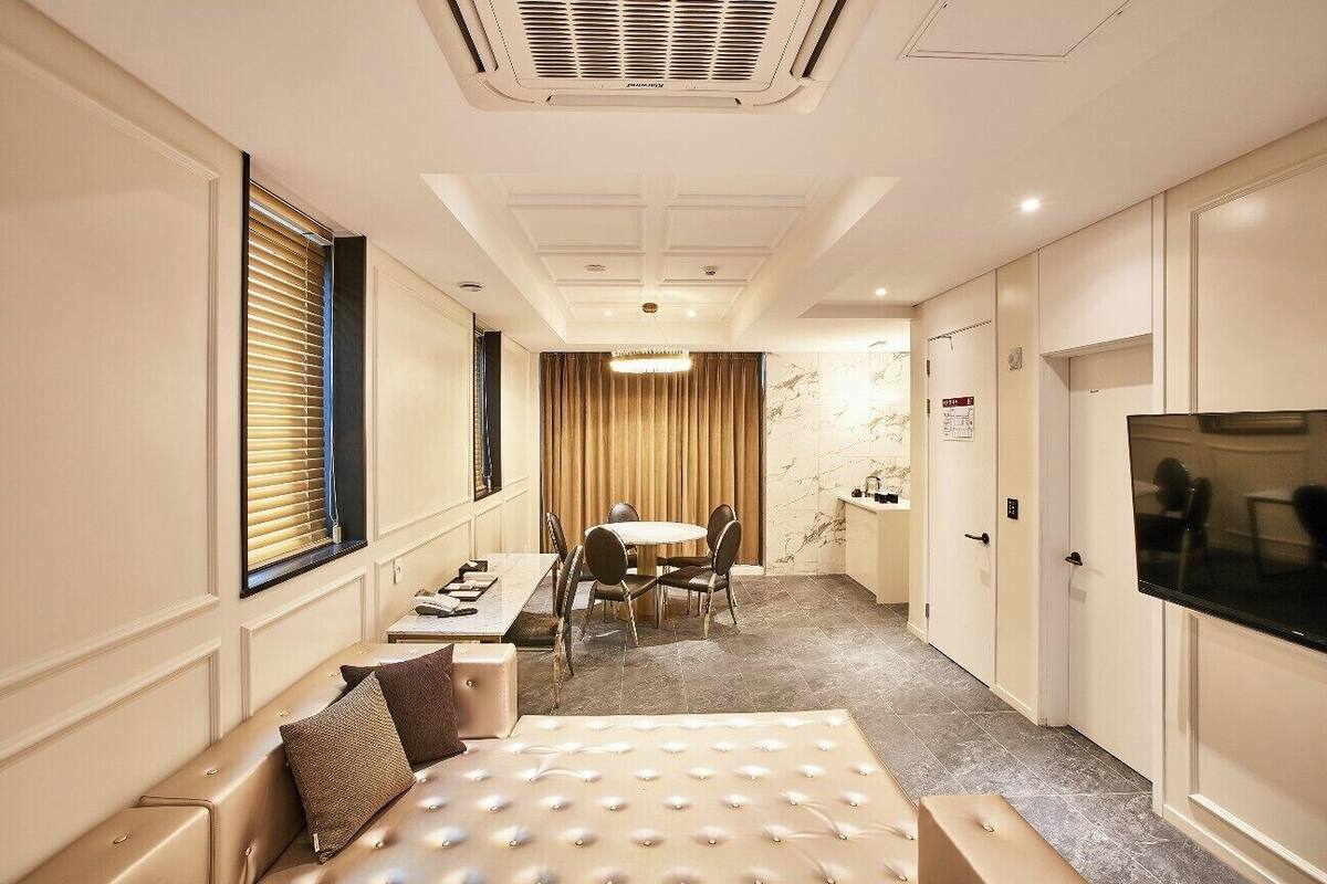 Une chambre d’hôtel dotée d’un grand lit, d’un coin repas avec une table et des chaises, d’une télévision et d’un minibar.