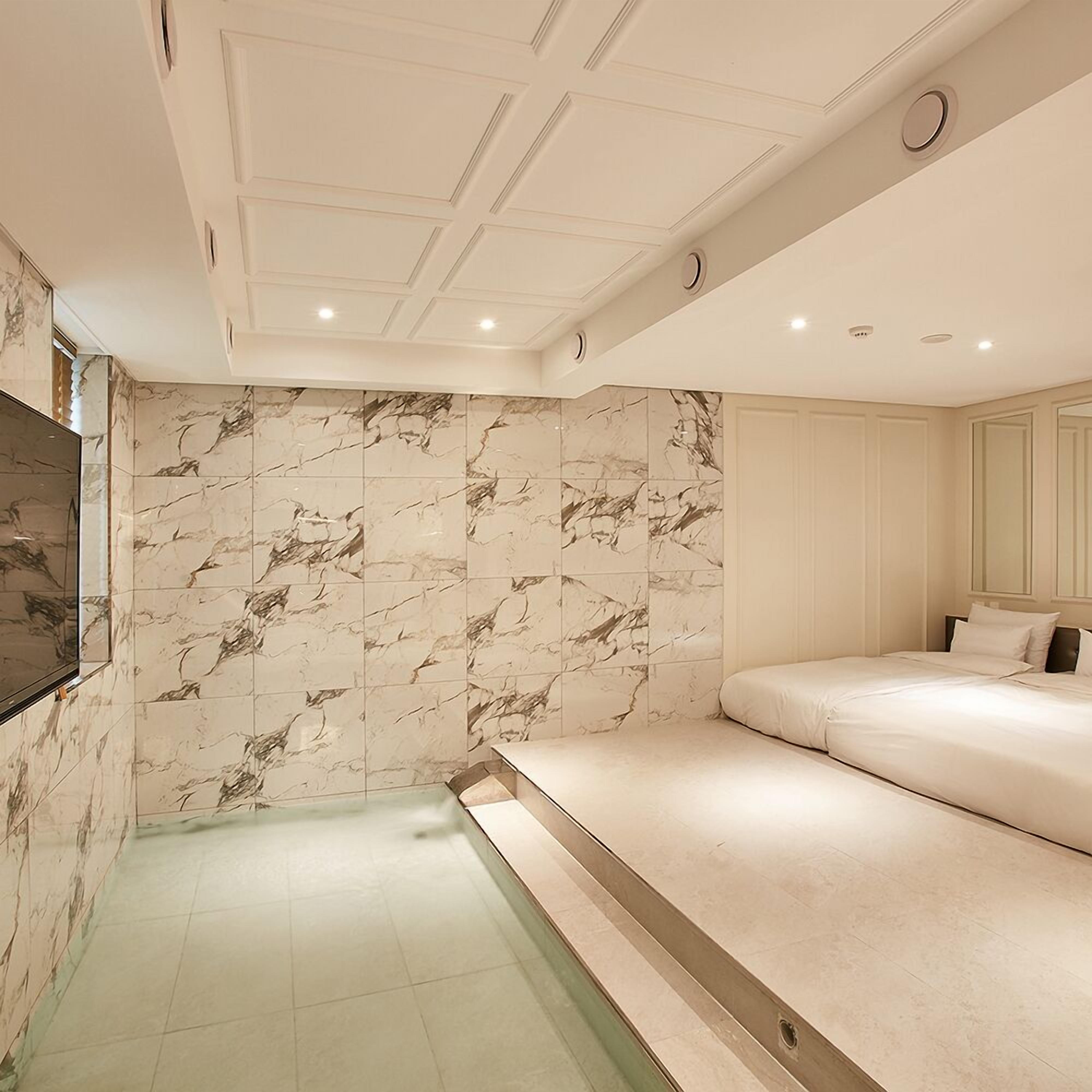 Une salle de bain moderne avec un mur en marbre, une baignoire et un grand miroir.