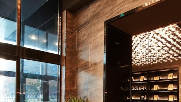 Um lobby moderno com parede de vidro, planta em vaso, estante e área de estar.