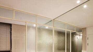 A modern bathroom with a glass partition, a bathtub, a sink, and a mirror.