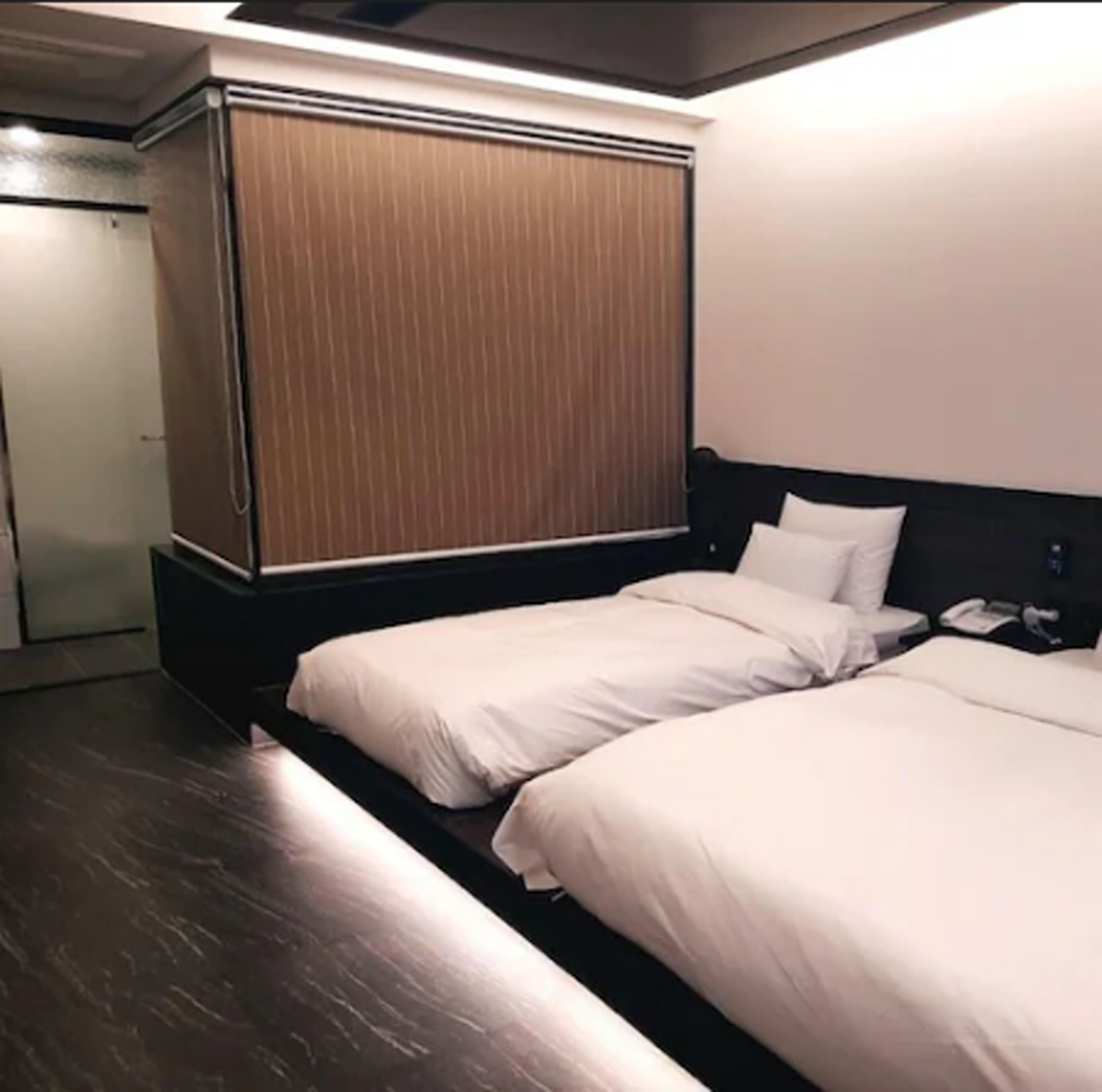Una habitación de hotel con dos camas, un armario de madera y un escritorio pequeño con teléfono.