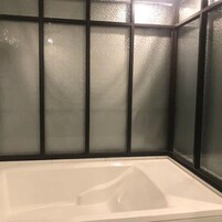 A bathtub with a glass enclosure and a black frame.