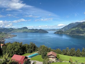 Ein Anwesen am See mit einem großen Haus, einem Schwimmbad und umgebender Bepflanzung.