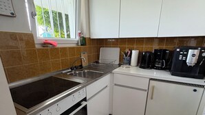 Eine Küche mit weißen Schränken, einem Herd, einer Spüle und einer Kaffeemaschine.