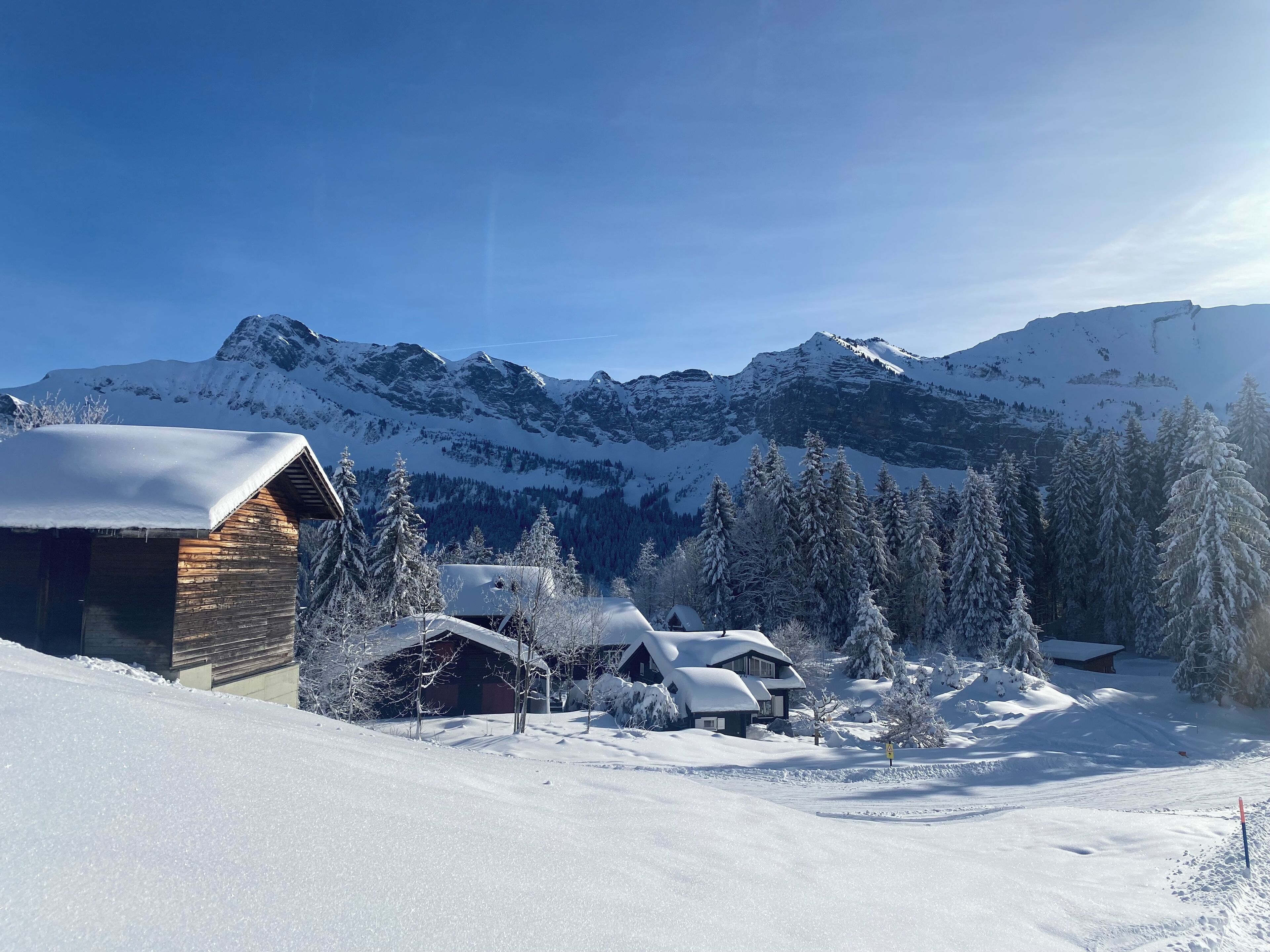 Un paisaje montañoso nevado con una cabaña de madera y varias casas.