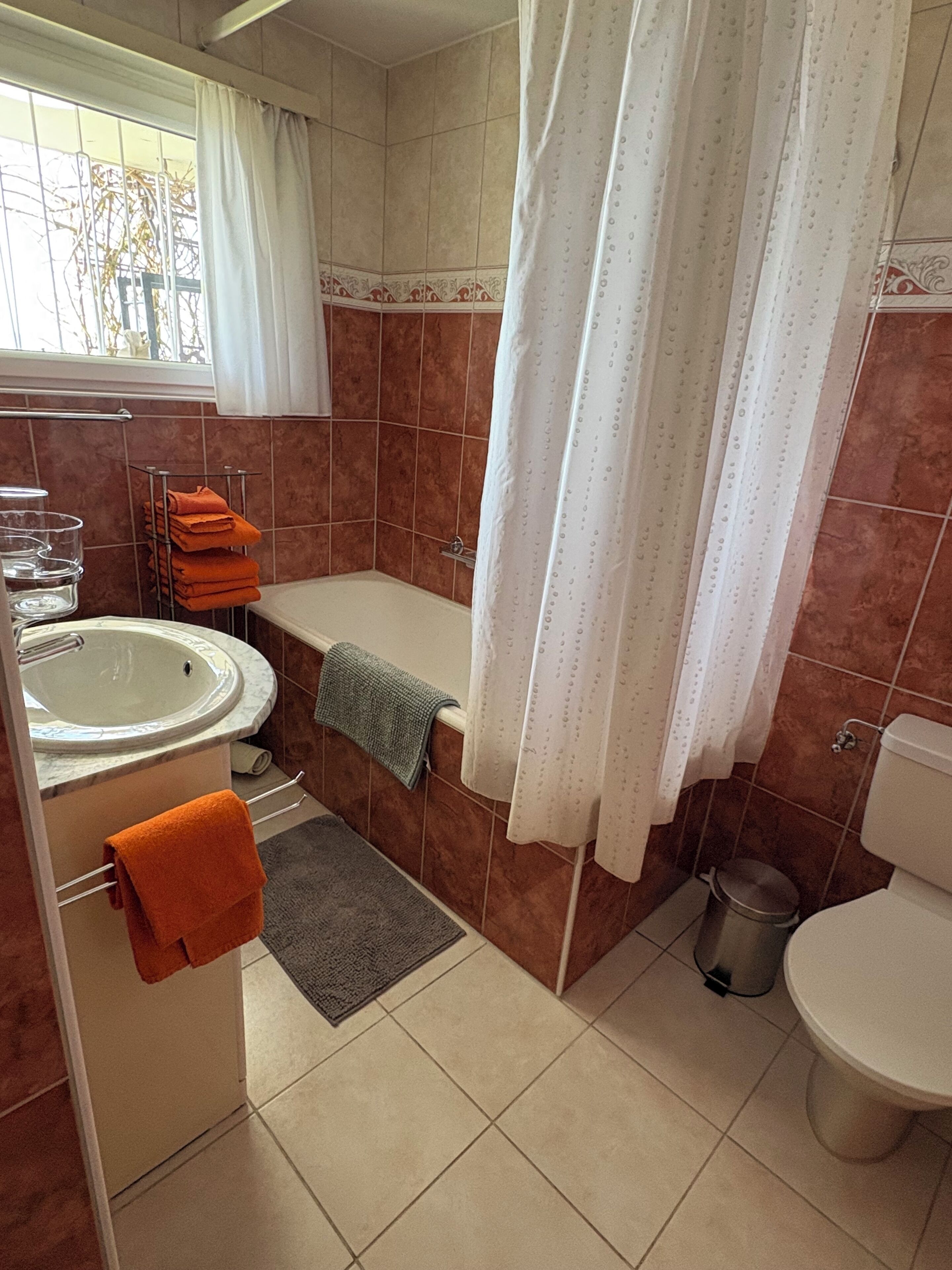 A bathroom with a bathtub, toilet, sink, and a window with a view.