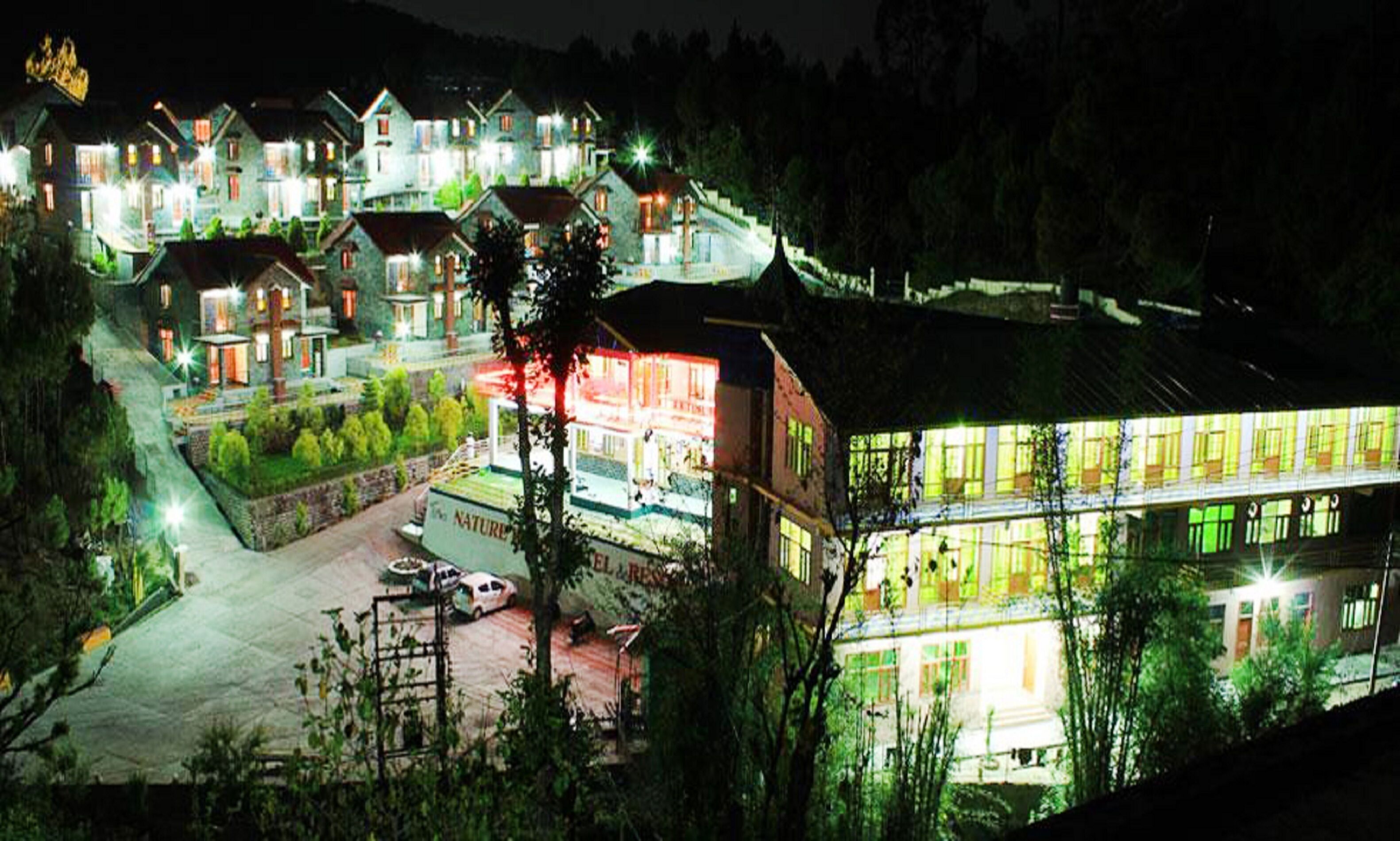 A hotel with multiple buildings, a parking area, and a natural surrounding.