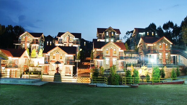 A row of multi-story houses with balconies, a well-maintained lawn, and a clear sky. - Nature Bloom Dharamshala Hotel and Resort (Palampur)