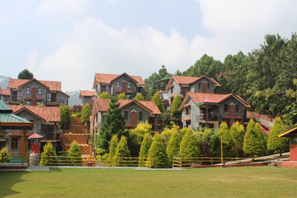 A residential area with multiple houses, each with a red-tiled roof, surrounded by greenery and trees.