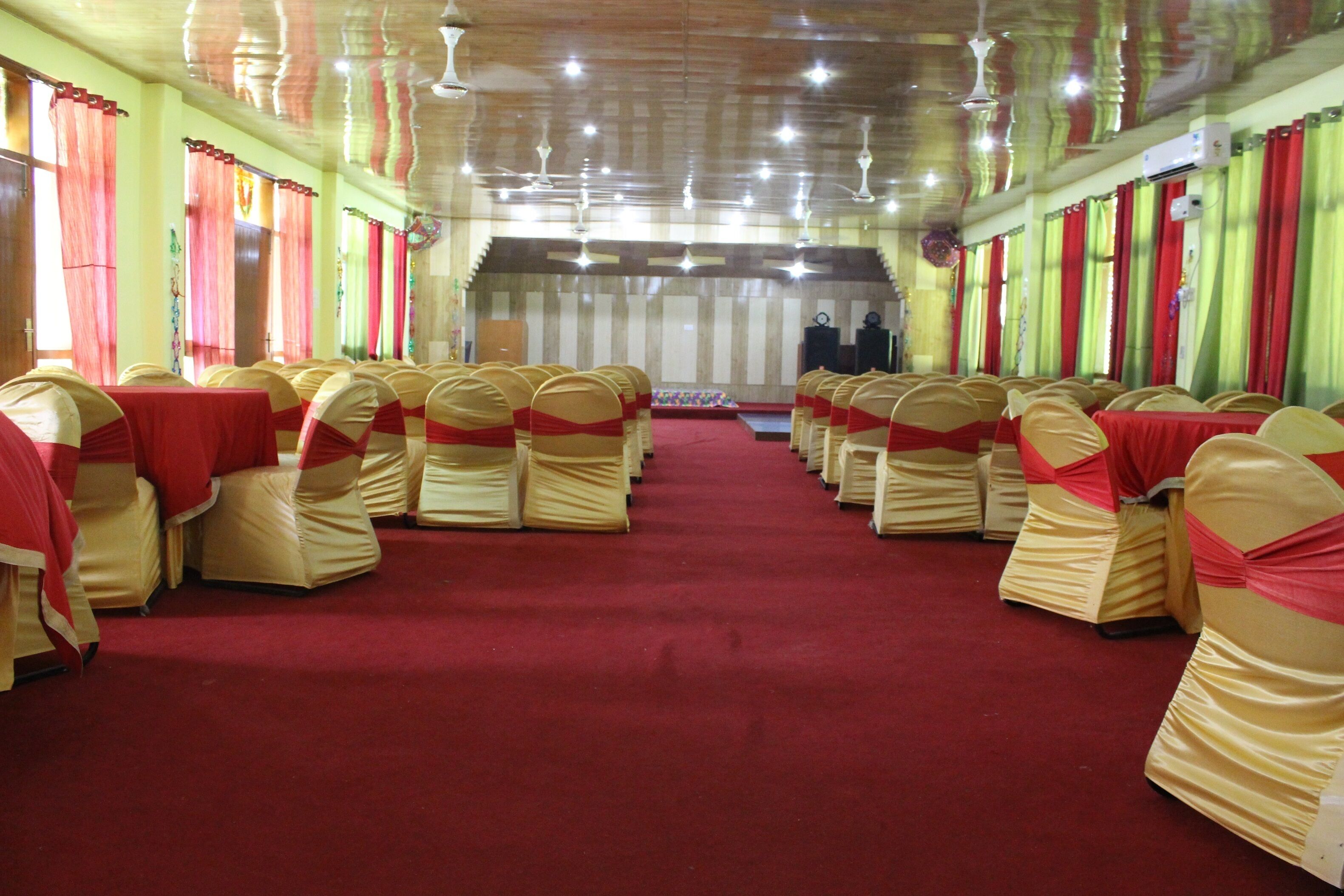 Une salle avec des rangées de chaises et une scène.