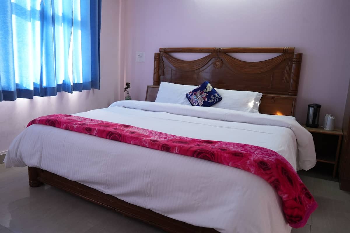 Una cama bien hecha con ropa de cama blanca y rosa, un cabecero de madera y una mesita de noche con una lámpara y un cubo de basura.