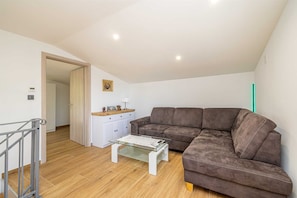 A living room with a brown sofa, a glass coffee table, a white cabinet, and a wooden floor. - Holiday house MICHAEL with shared pool and private jacuzzi (Pinezići)