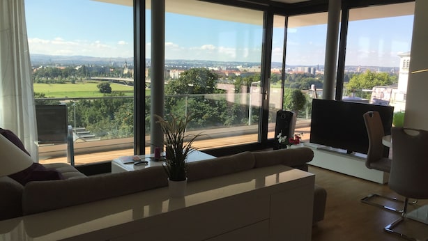 Een moderne woonkamer met een groot raam dat uitzicht biedt op de stad.
