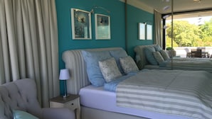 Een slaapkamer met een groot bed, een stoel, een nachtkastje en een spiegel.