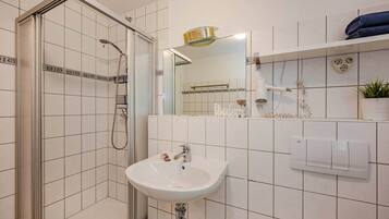 Ein Badezimmer mit Dusche, Waschbecken, Spiegel und Handtuchhalter.
