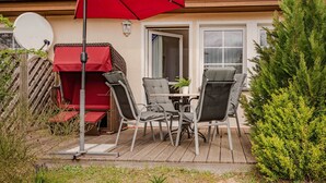 Un patio con una mesa, sillas, un paraguas rojo y una antena parabólica.