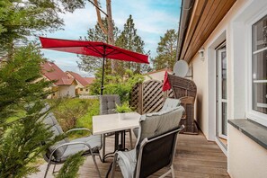 Une terrasse avec une table et des chaises, un parasol rouge et une vue sur les maisons voisines.