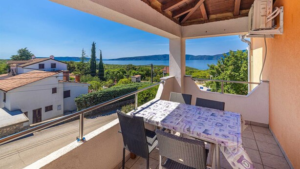 A balcony with a table and chairs, overlooking a scenic view of a lake and surrounding buildings. - Apartment JENNY 1 with pool and sea view (Pinezici)