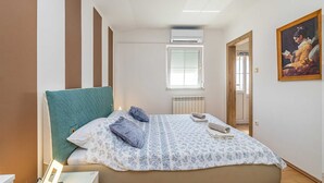 A bedroom with a bed, a radiator, an air conditioning unit, a window, and a painting on the wall. - Apartment JENNY 1 with pool and sea view (Pinezici)