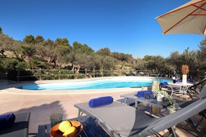 A poolside area with lounge chairs, a table with a bowl of fruit, and a clear view of the swimming pool. - Finca Lourdes, quiet location, pool, air conditioning, 5 bedrooms, 5 bathrooms (Pollença)