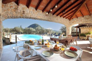 An outdoor dining area with stone arches, a pool, and a mountain view. - Finca Lourdes, quiet location, pool, air conditioning, 5 bedrooms, 5 bathrooms (Pollença)