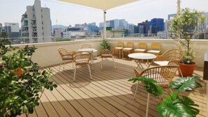 A rooftop terrace with outdoor seating, potted plants, and a city skyline view. - Tong Tong Petit Hotel (Seoul)