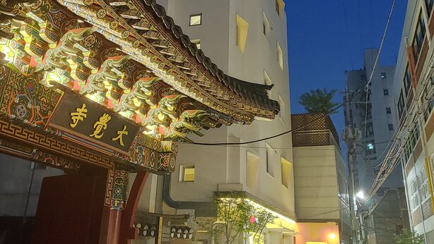 A hotel with a traditional ornate entrance and a modern building in the background. - Tong Tong Petit Hotel (Seoul)