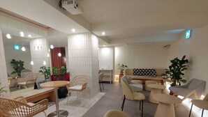 A modern living room with a round table, wicker chairs, a sofa, and a large mirror. - Tong Tong Petit Hotel (Seoul)