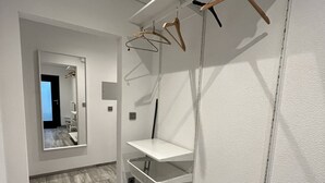 Une salle de bain moderne et minimaliste, dotée d’une étagère intégrée, d’un porte-serviettes suspendu et d’un miroir.
